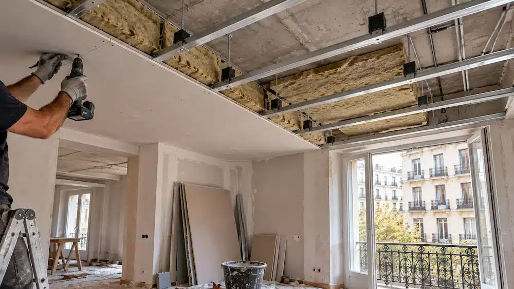 Instalación de un falso techo acústico con lana mineral y soportes antivibratorios en el salón de un piso
